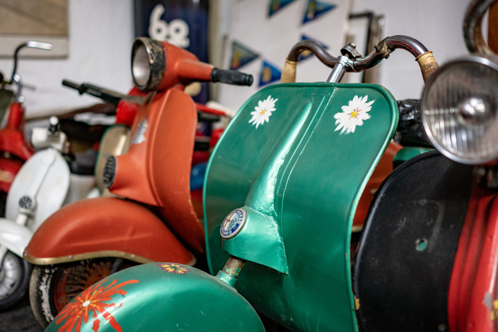 Auf dem Bild sind mehrere alte Vespas in weiß, rot und grün zu nebeneinander zu sehen.