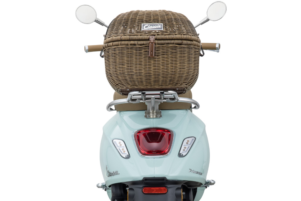 Rückansicht einer hellblauen Vespa mit braunem Gepäckkorb in Picknick-Optik.