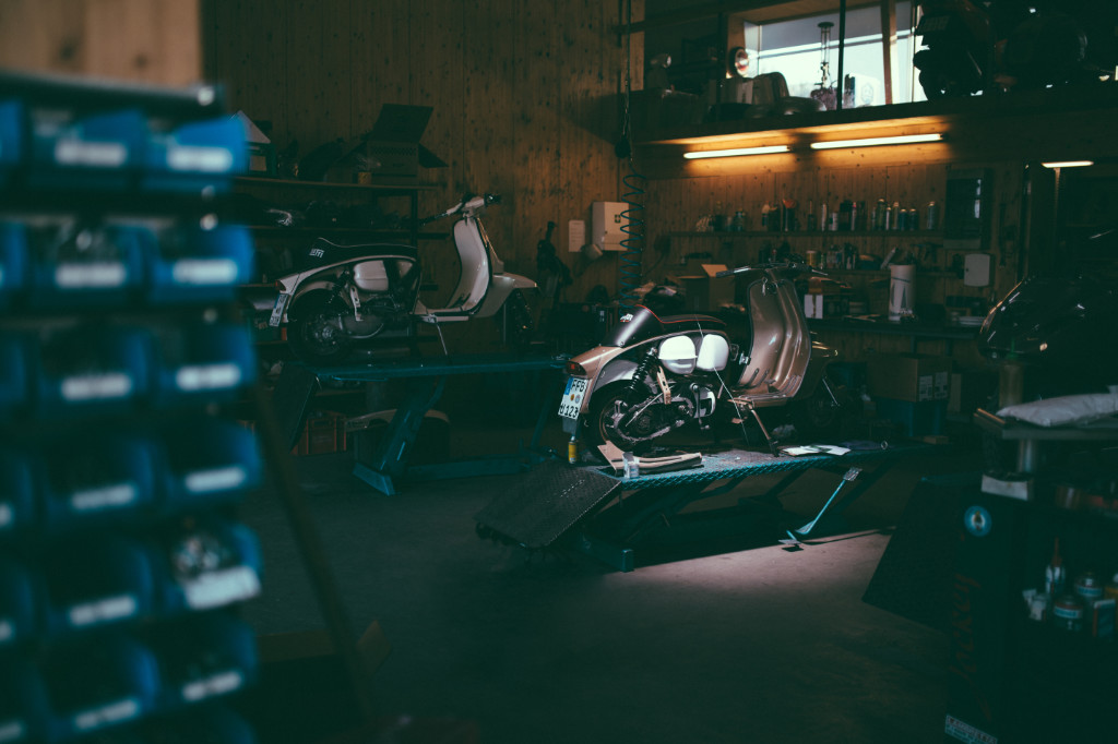 Dark Vespa workshop, with a Vespa in the centre with the light shining on it