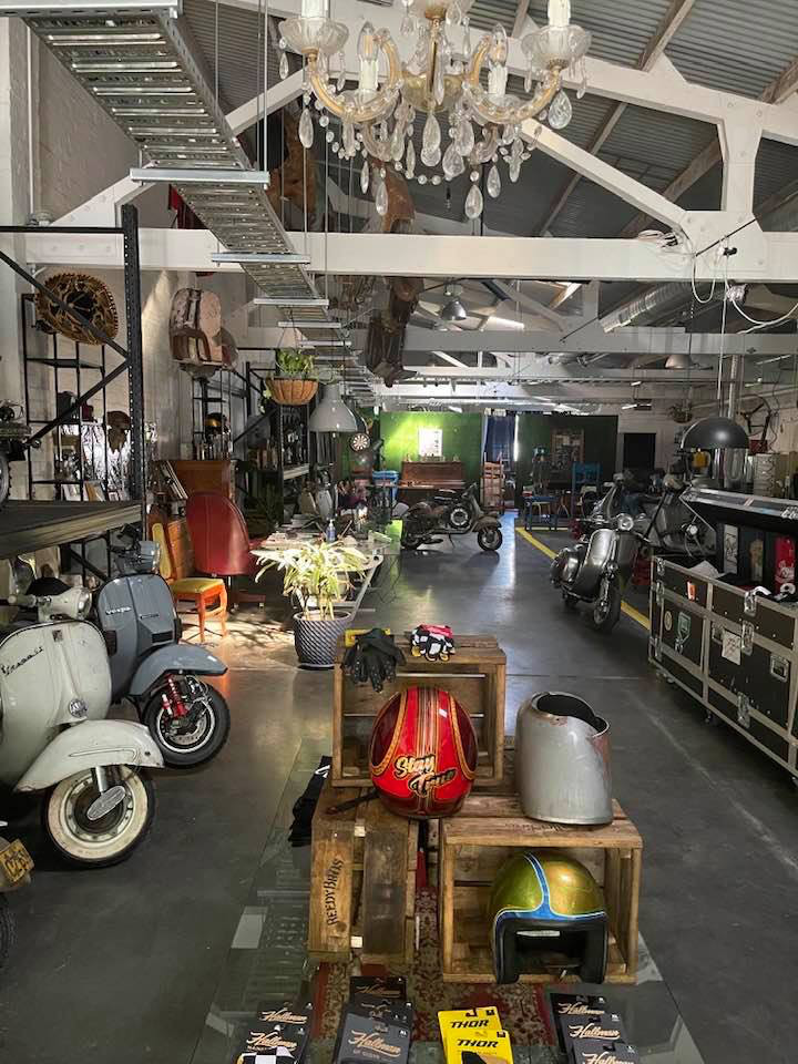 Scooter Meccanica interior with Vespas on display, accessories, a chandelier, plants and seating