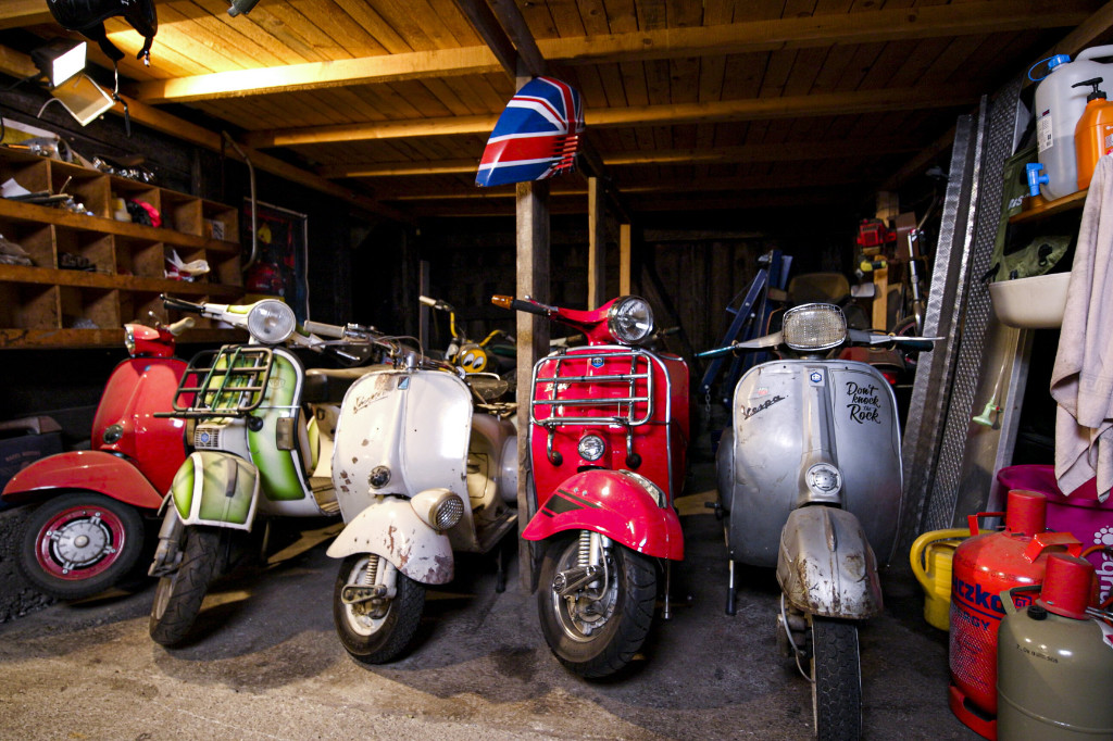 Various Vespas lined up next to each other in a workshop.