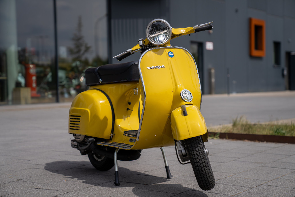 Yellow Vespa parked in front of a building