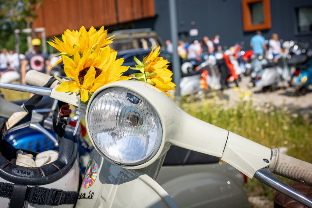 Nahaufnahme Vespa Frontscheinwerfer mit Blumen daneben