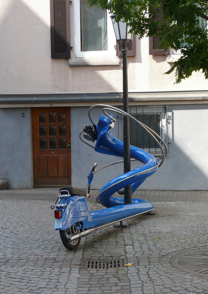 Blaue Vespa kunstvoll um einen Laternenmast gedreht