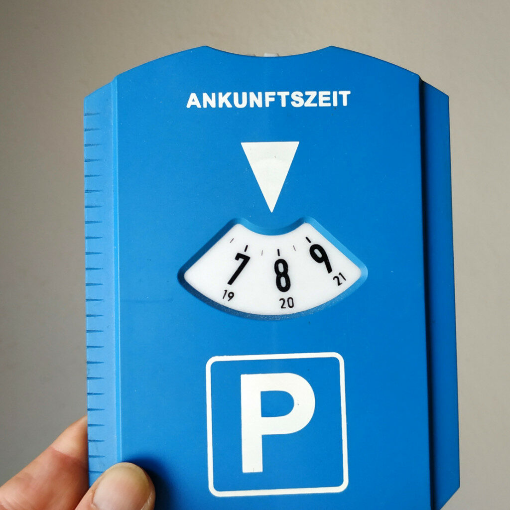 eine Hand hält eine blaue Parkscheibe