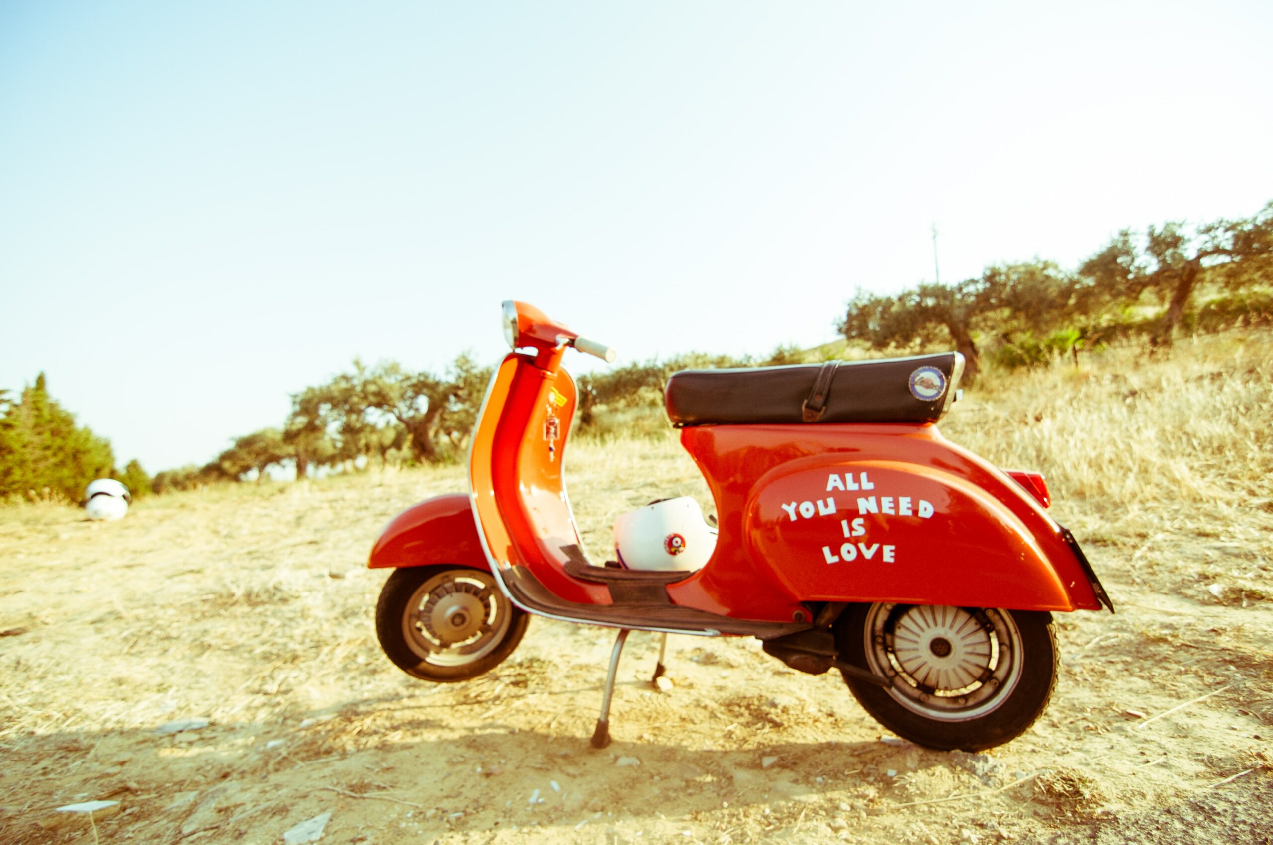 Red Vespa standing in a deserted area with a blue sky