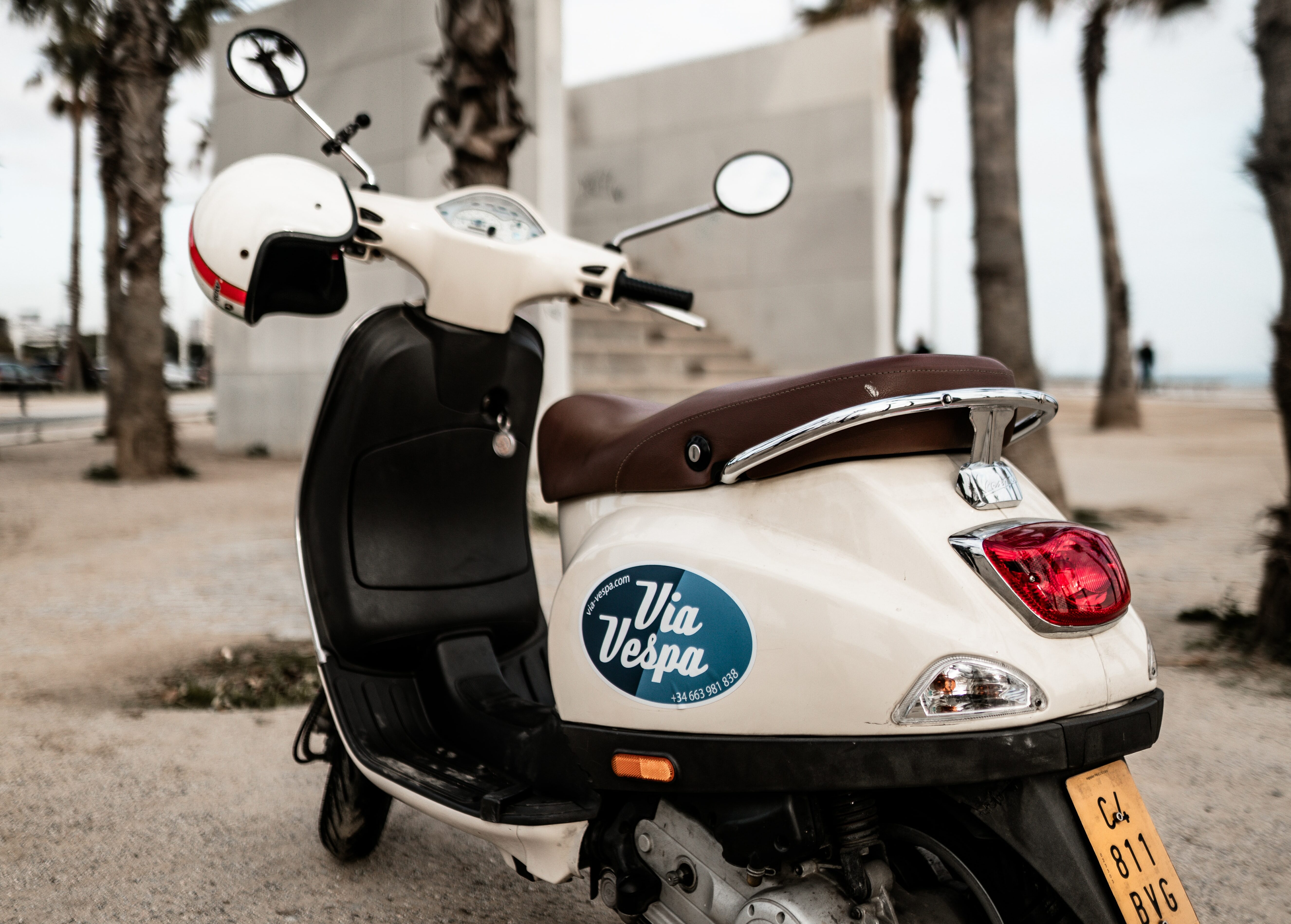 white Vespa with foiling infront of palm trees