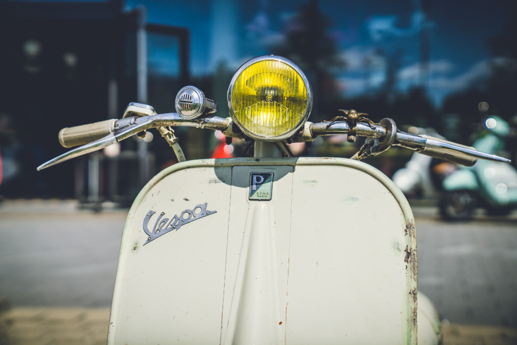 Eine alte Vespa von vorne mit gelbem Scheinwerfer.