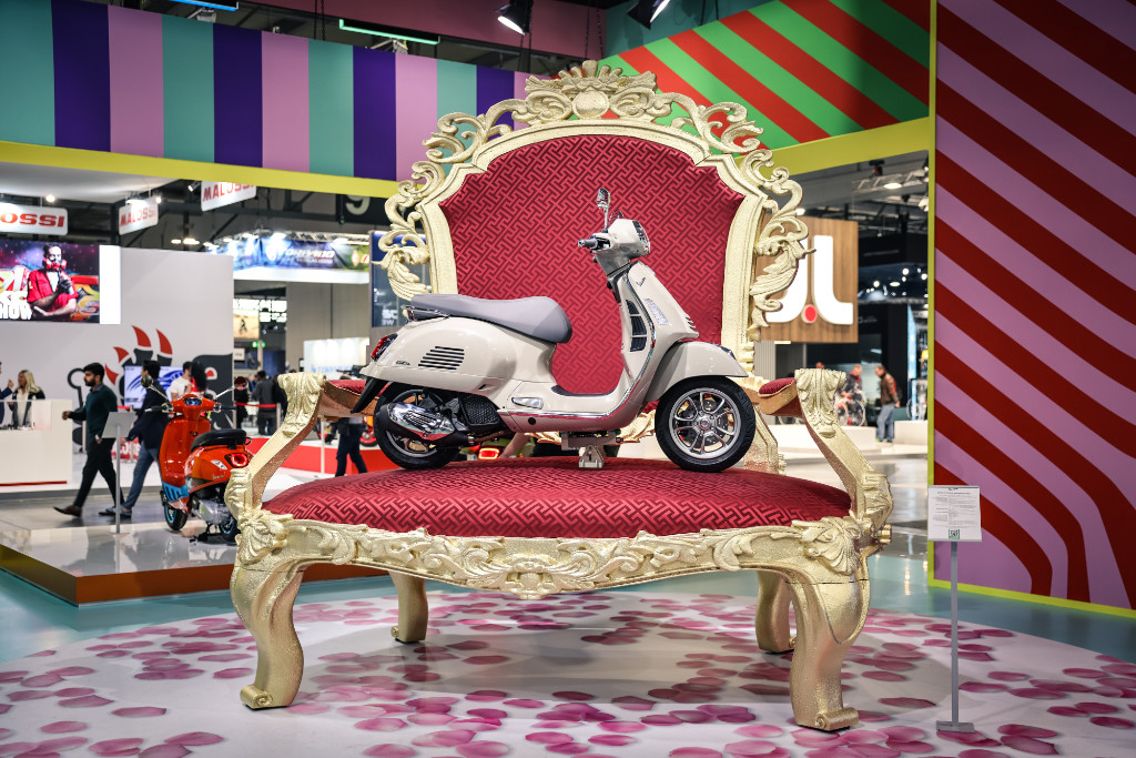 Vespa GTS on a huge golden throne with red upholstery at the EICMA 22
